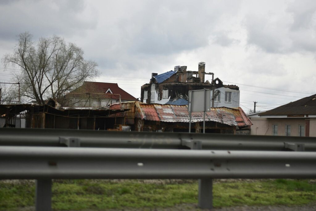 A highway view of fire-damaged residential buildings with cloudy skies.
